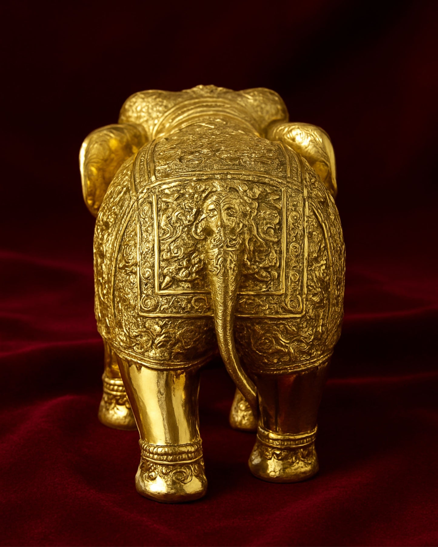 Decorative gold elephant figurine on a red fabric background