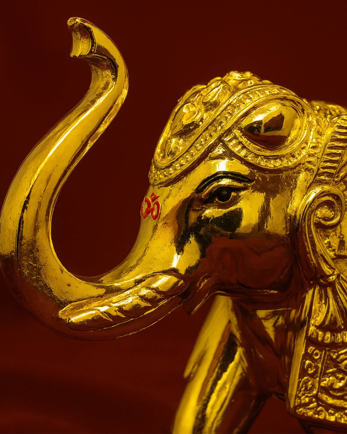Gold elephant statue with detailed head on a red background