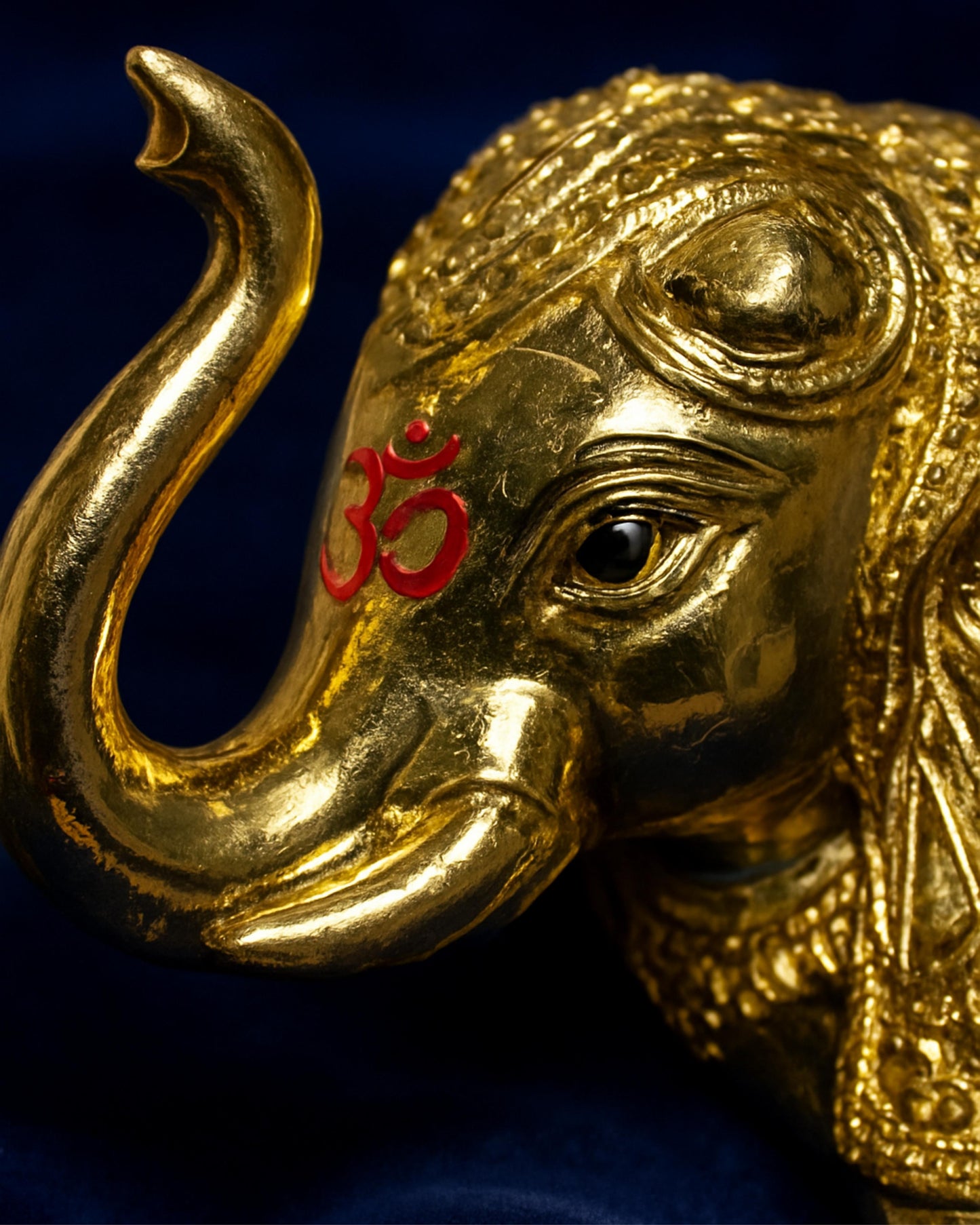 Gold elephant figurine with a red symbol on a dark background