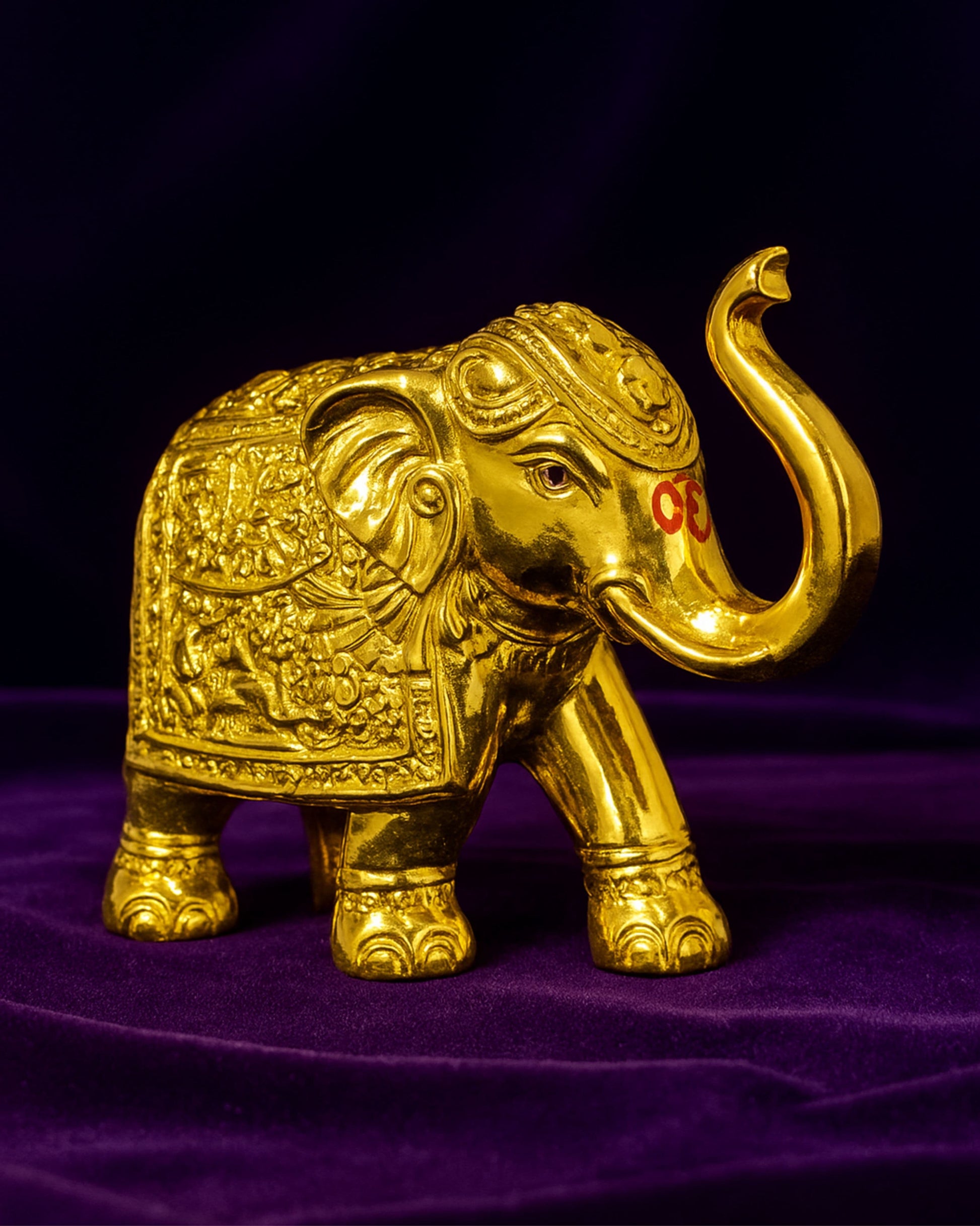 Decorative gold elephant figure on a purple fabric background